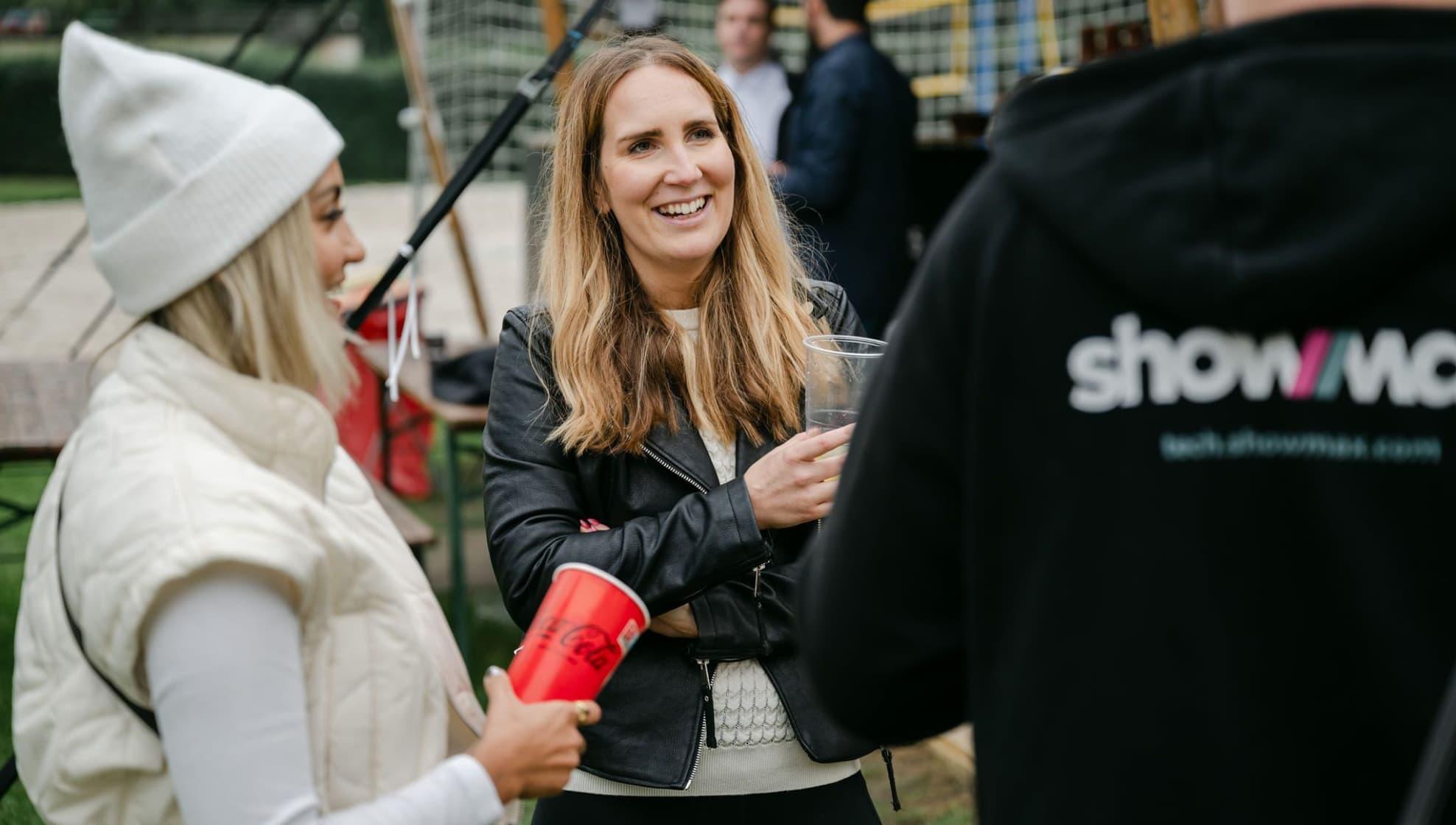 two women and a person wearing a Showmax hoodie in conversation and laughing together